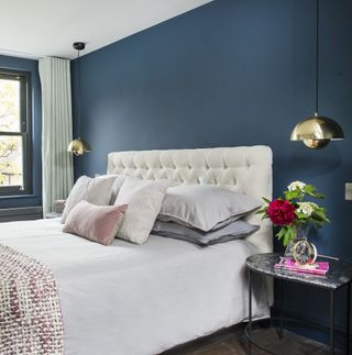 Blue bedroom with two pendant lights and white upholstered headboard