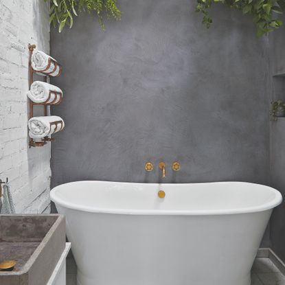 A freestanding bath with green hanging plants