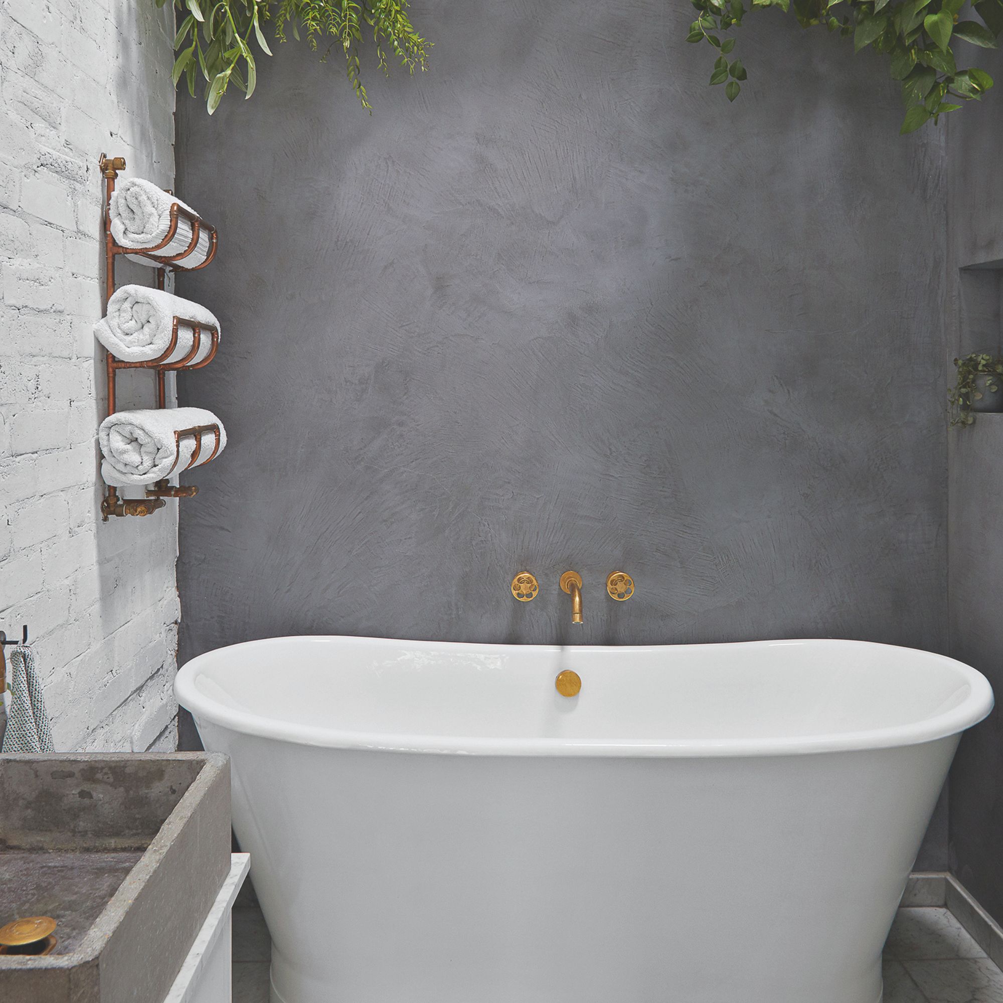 A freestanding bath with green hanging plants