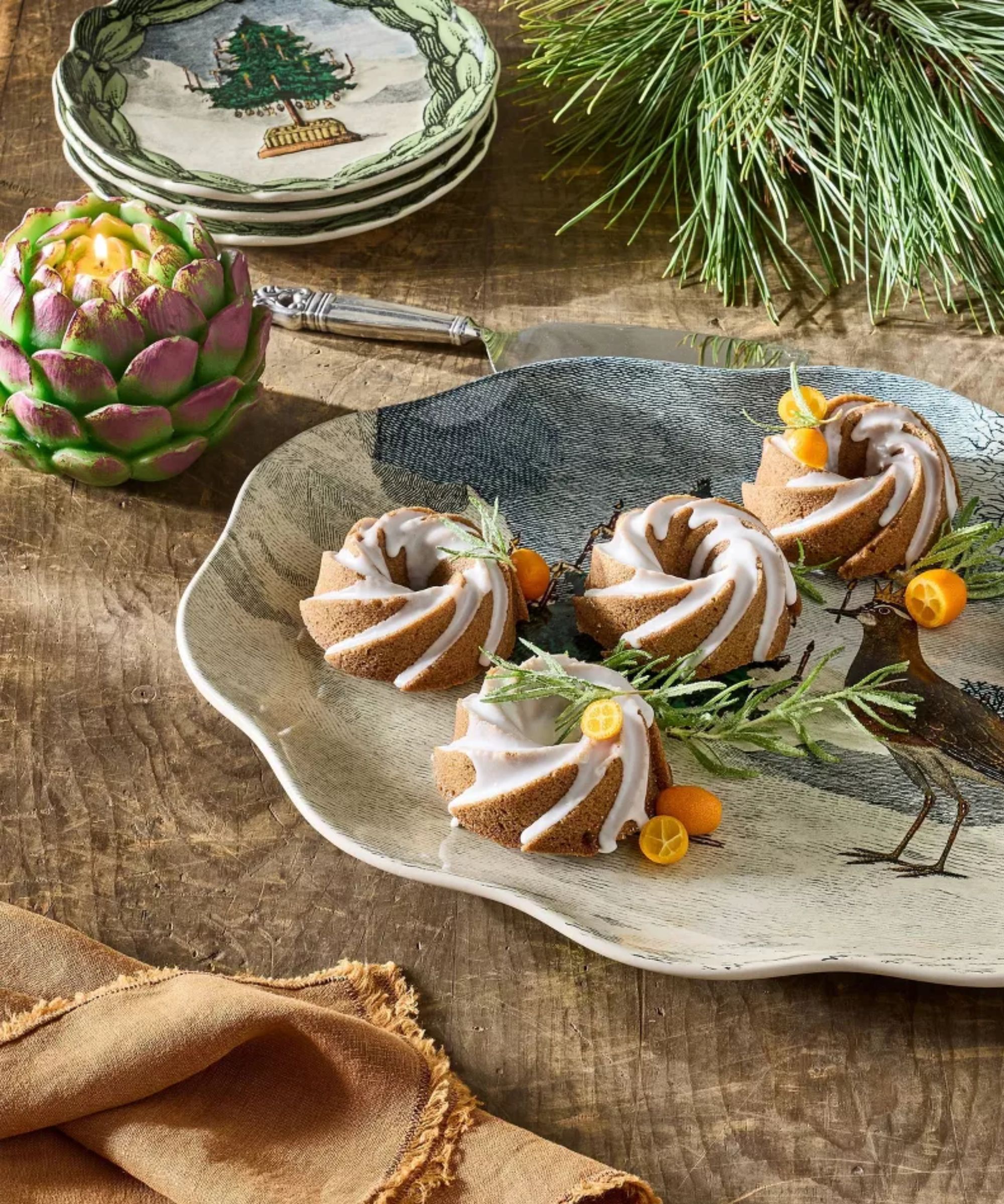 Christmas platter holding mini bundt cakes, next to an artichoke-shaped candle