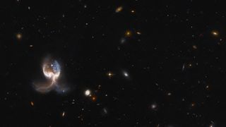 The NASA/ESA Hubble Space Telescope photographed the VV689 system, which consists of two massive merging galaxies, giving the system a symmetrical "wing" appearance. 