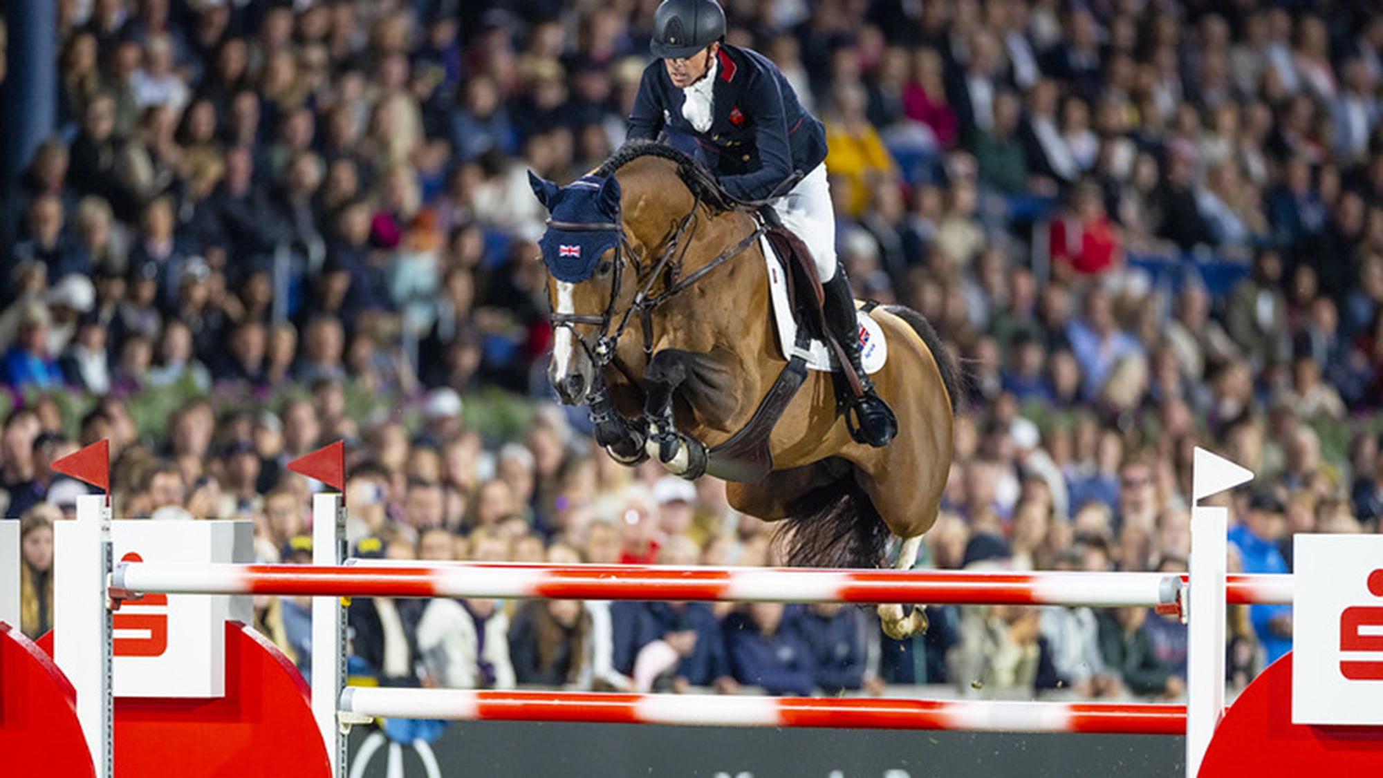 Ben Maher and Point Break, a light bay horse, jump a red and white fence at the showjumping World Championships in Aachen