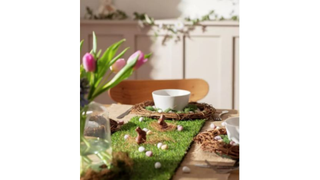 A table decorated for an Easter meal with flowers, chocolate bunnies and the Argos Home Table Runner, which looks like grass
