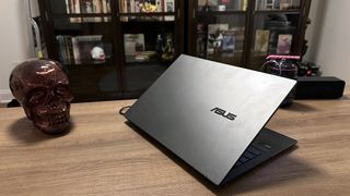 Asus Zenbook 14 OLED (Q425M) open on a wood desk angled away from the camera with lid slightly open