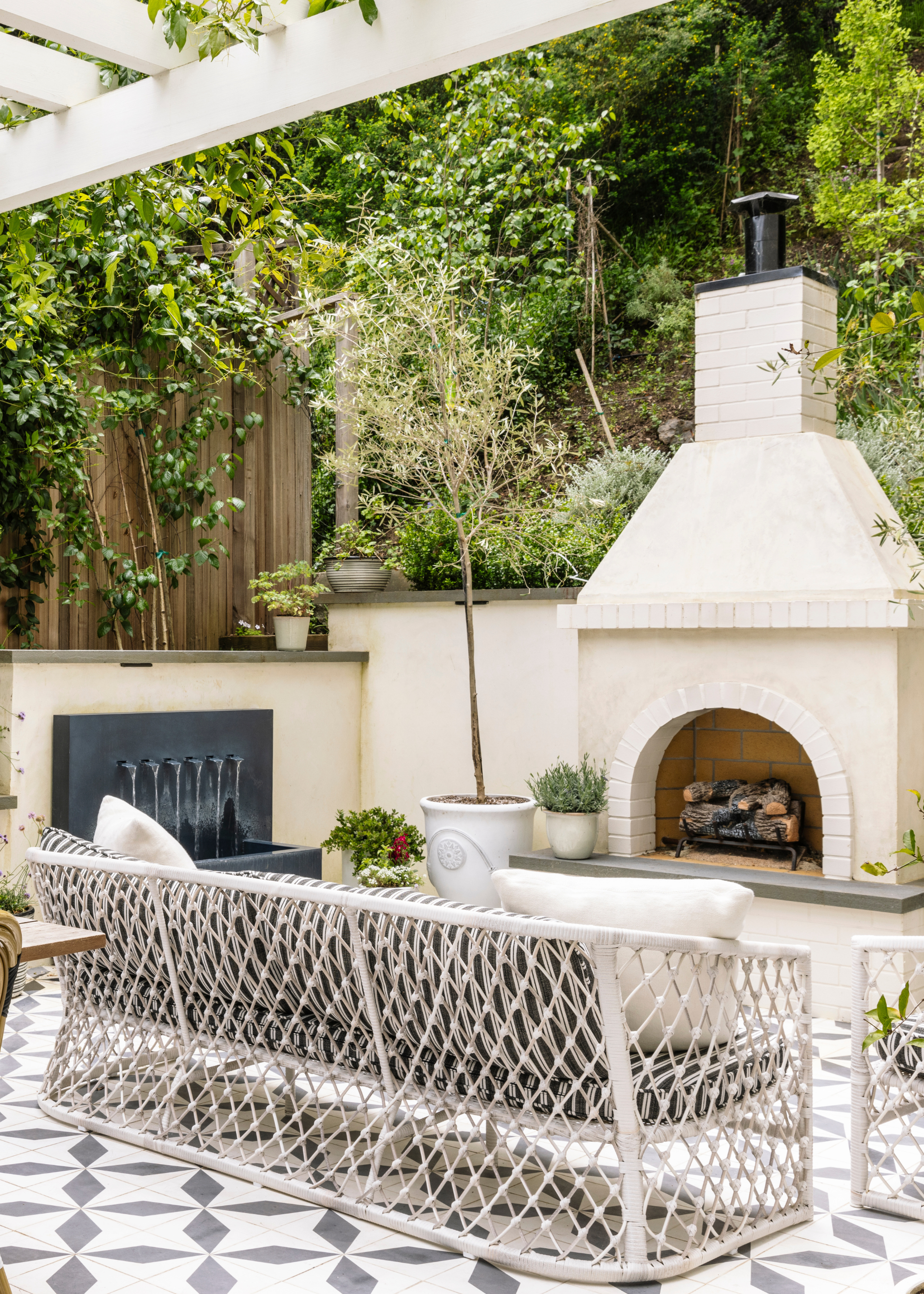 outdoor living room with a large fireplace, a water fountain, and tiled floors