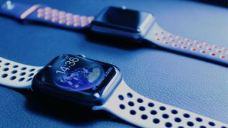 Two Apple Watch series 7 wearables on a blue surface