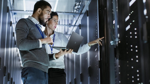Male IT specialist with female server technician standing in data center
