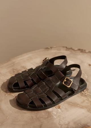 a pair of brown leather fisherman sandals by me+em in front of a plain backdrop
