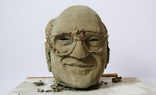 Clay sculpture of male face wearing glasses