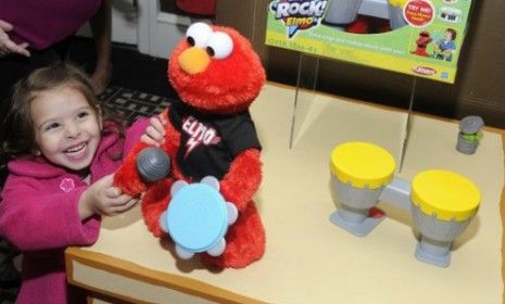 A girl plays with Let&amp;#039;s Rock Elmo at the toy&amp;#039;s launch party: When held close to the ear, noisy playthings like Elmo can damage young children&amp;#039;s hearing, according to researchers.