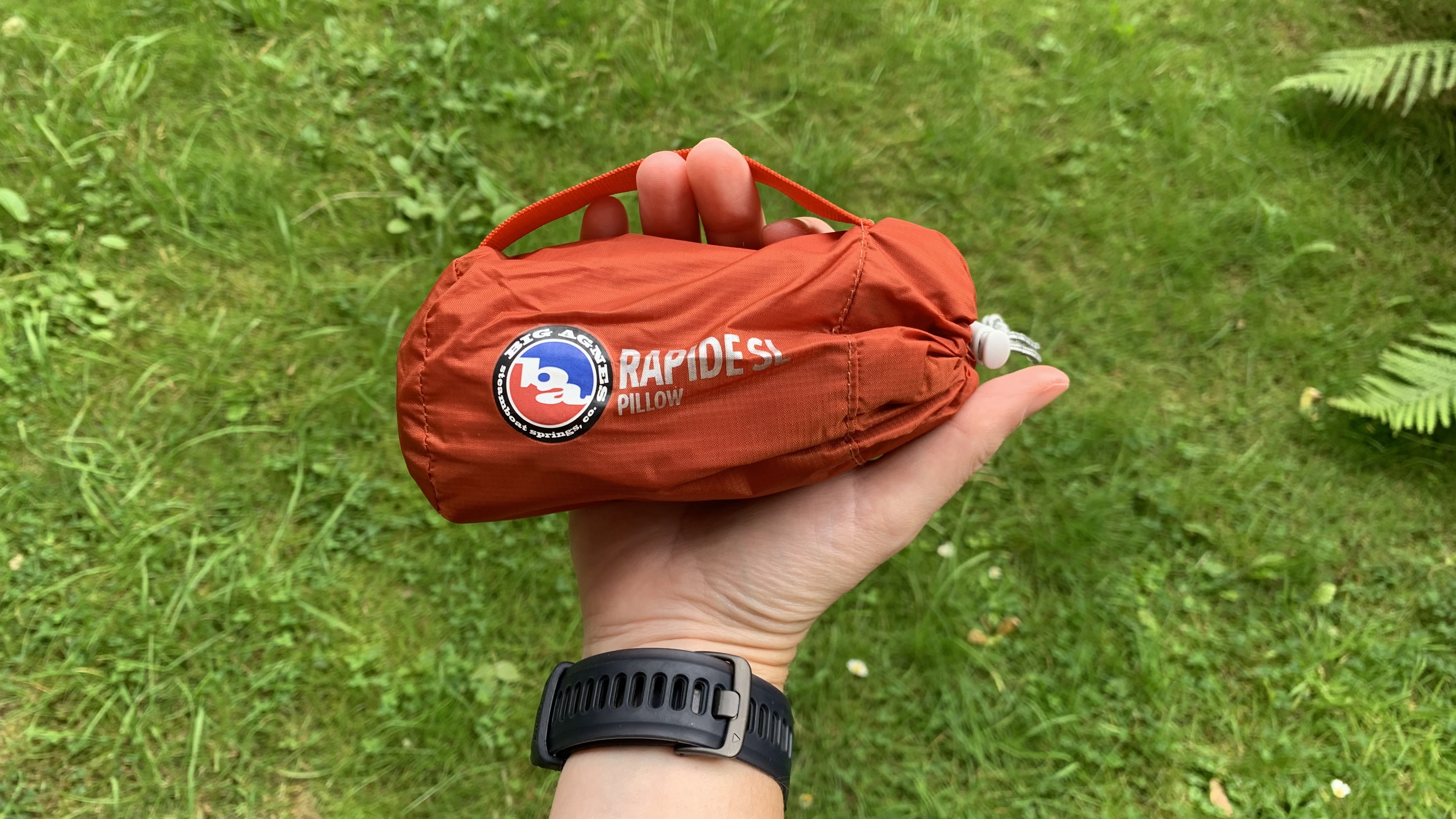 Hand holding the Big Agnes Rapide SL pillow it its stuff sack