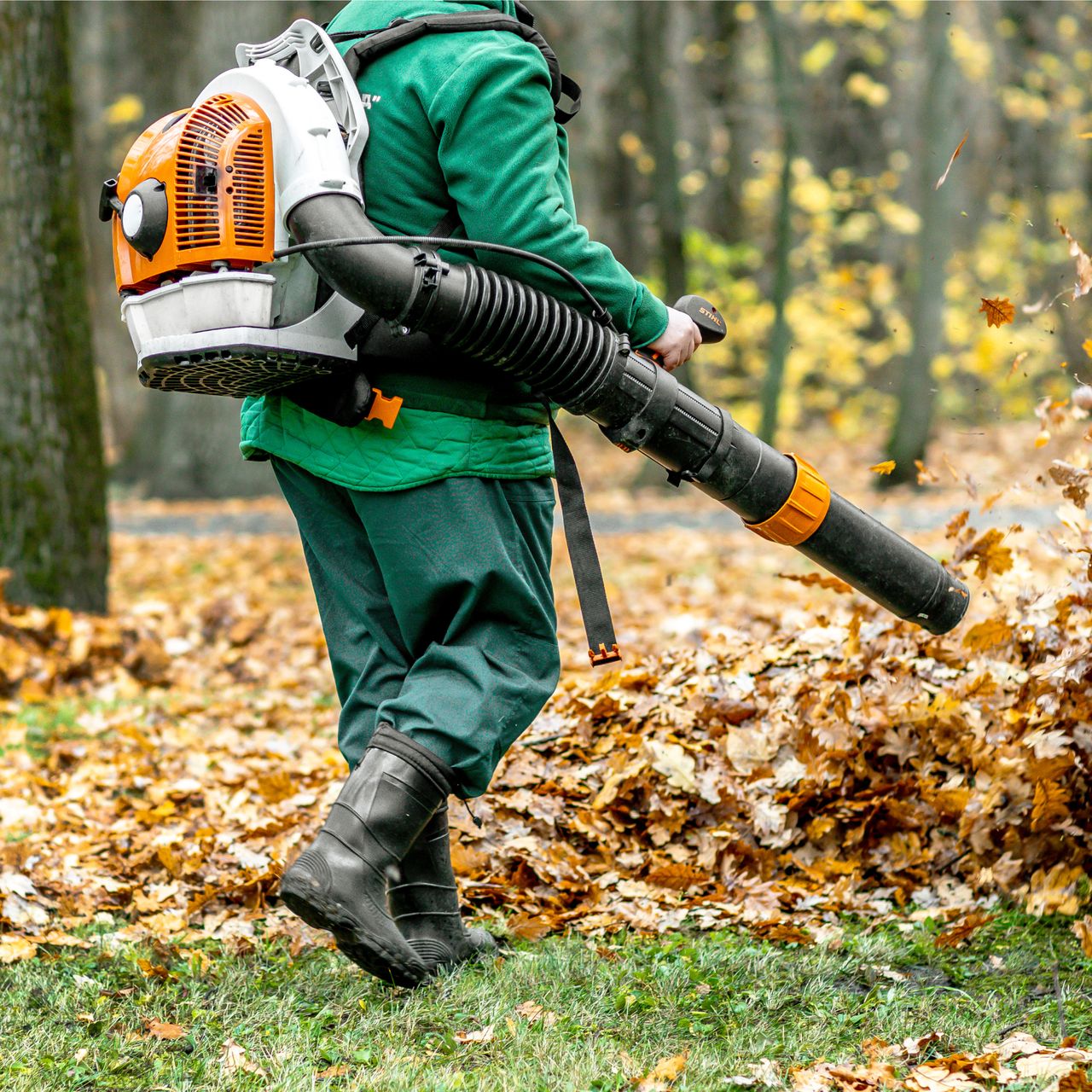 person blowing leaves with backpack blower