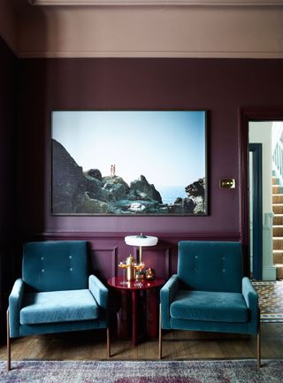 Dark purple room with sea print and navy blue velvet chairs