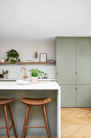 Pale sage green kitchen with island and marble countertops