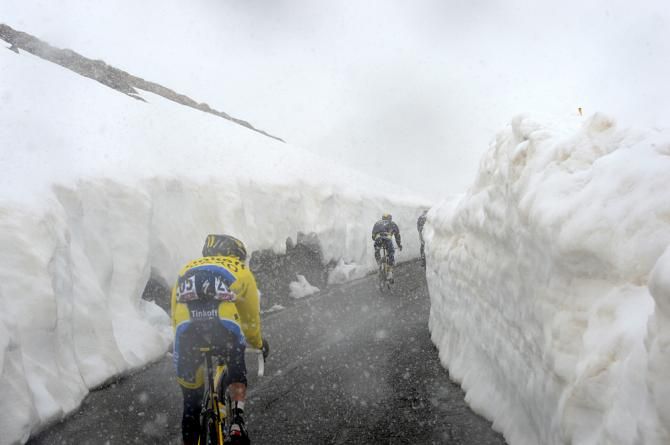 Tall banks of snow dwarf the riders atop the Passo Gavia