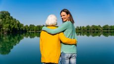 Mother and daughter embracing by a lake