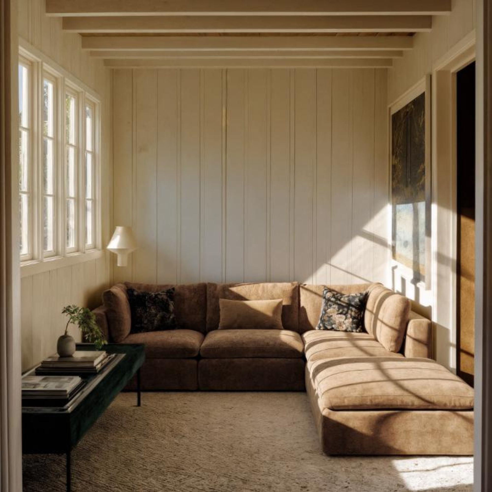 A neutral seating nook, with white walls and a mocha sofa