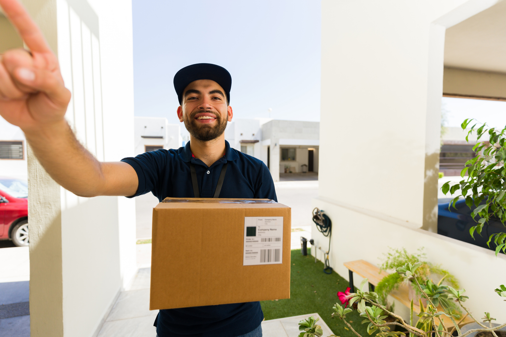 Courier in uniform rings a doorbell with a package