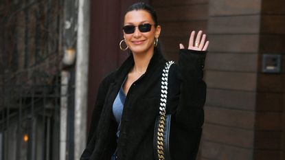 Bella Hadid wearing a black blazer with dark wash denim and a chain handbag