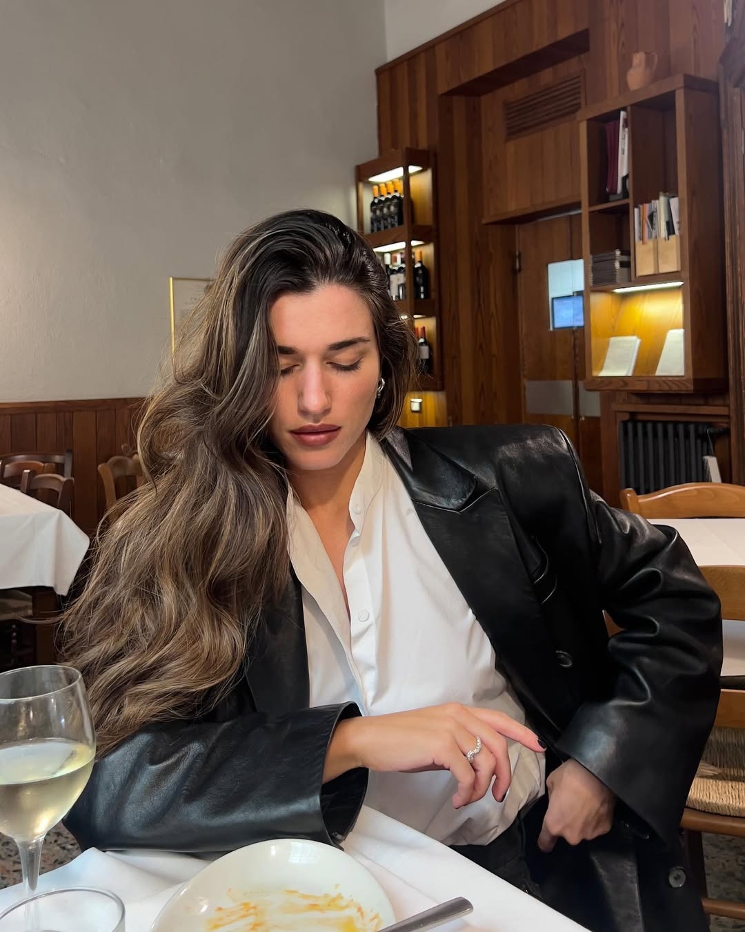 Woman with long hair styled in a blowout sitting at a dinner table.