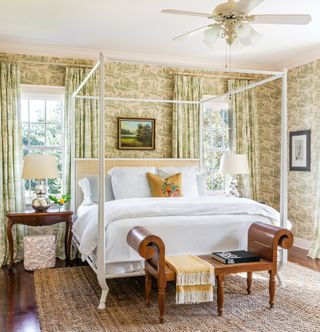 bedroom with white four poster bed and green floral wallpaper and curtains
