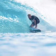 Prince Harry wearing a black wetsuit surfing a giant wave