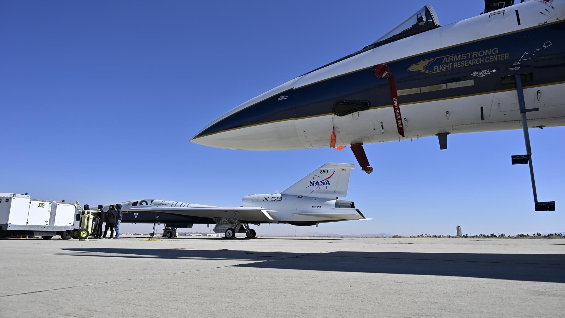 two sleek, small jets sit on a concrete tarmac in the desert