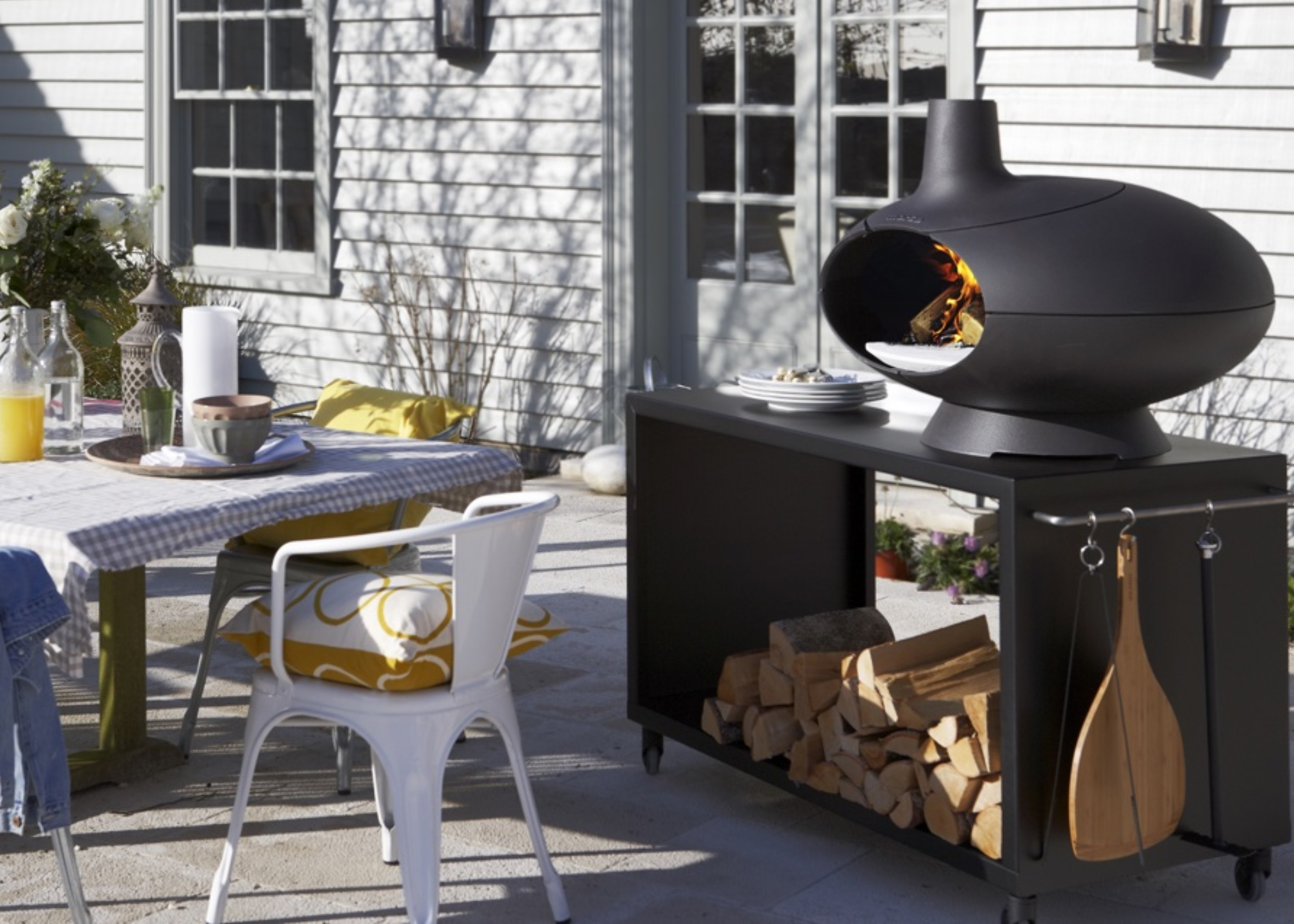 a swanky outdoor pizza oven design on top of wood storage on a patio
