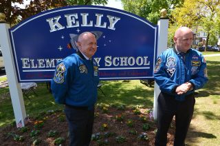 Twin astronauts Mark and Scott Kelly stand with the-newly revealed sign in front of Pleasantdale, now Kelly, Elementary School in West Orange, New Jersey, May 19, 2016.