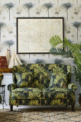 bold sofa in green palm tree print, map on wall, palm tree print wallpaper, boats, plants