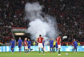 Players wait after a flare was thrown on to the pitch following England's third goal