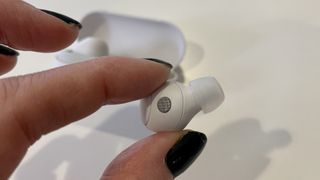 Sony WF-C700N earbuds in a hand, on white background