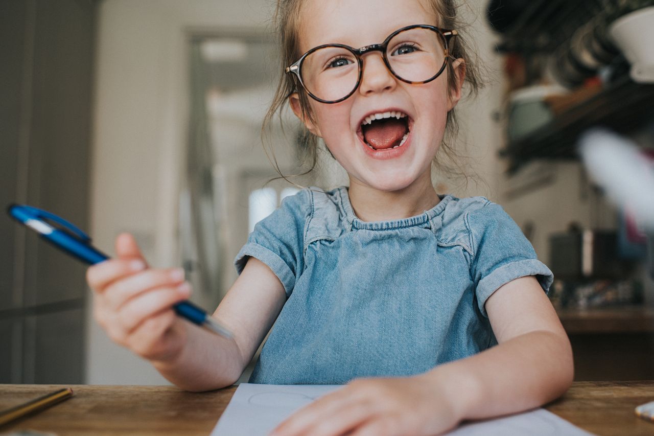 happy girl wearing glasses and holding a pen