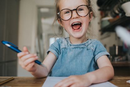 happy girl wearing glasses and holding a pen