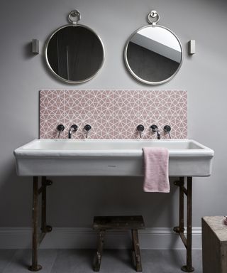 A bathroom backsplash idea with pink patterned tiles in neutral grey room