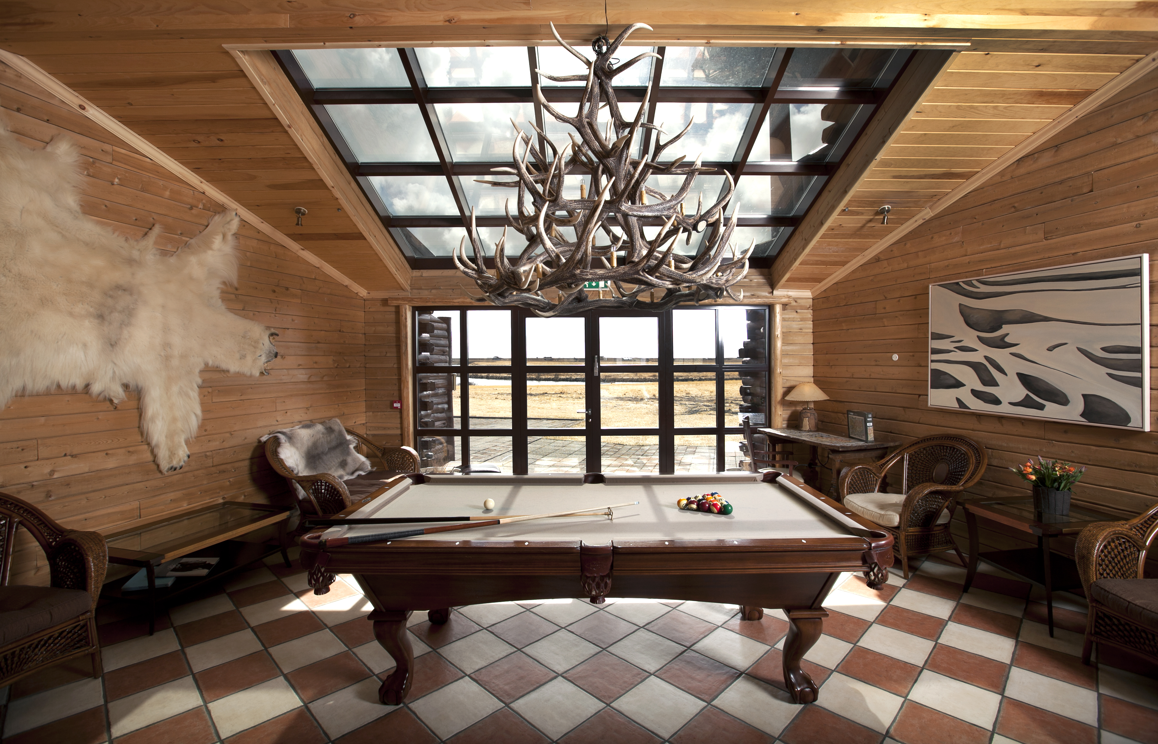 An antler chandelier hangs over a pool table in the game room at Hotel Ranga in Iceland