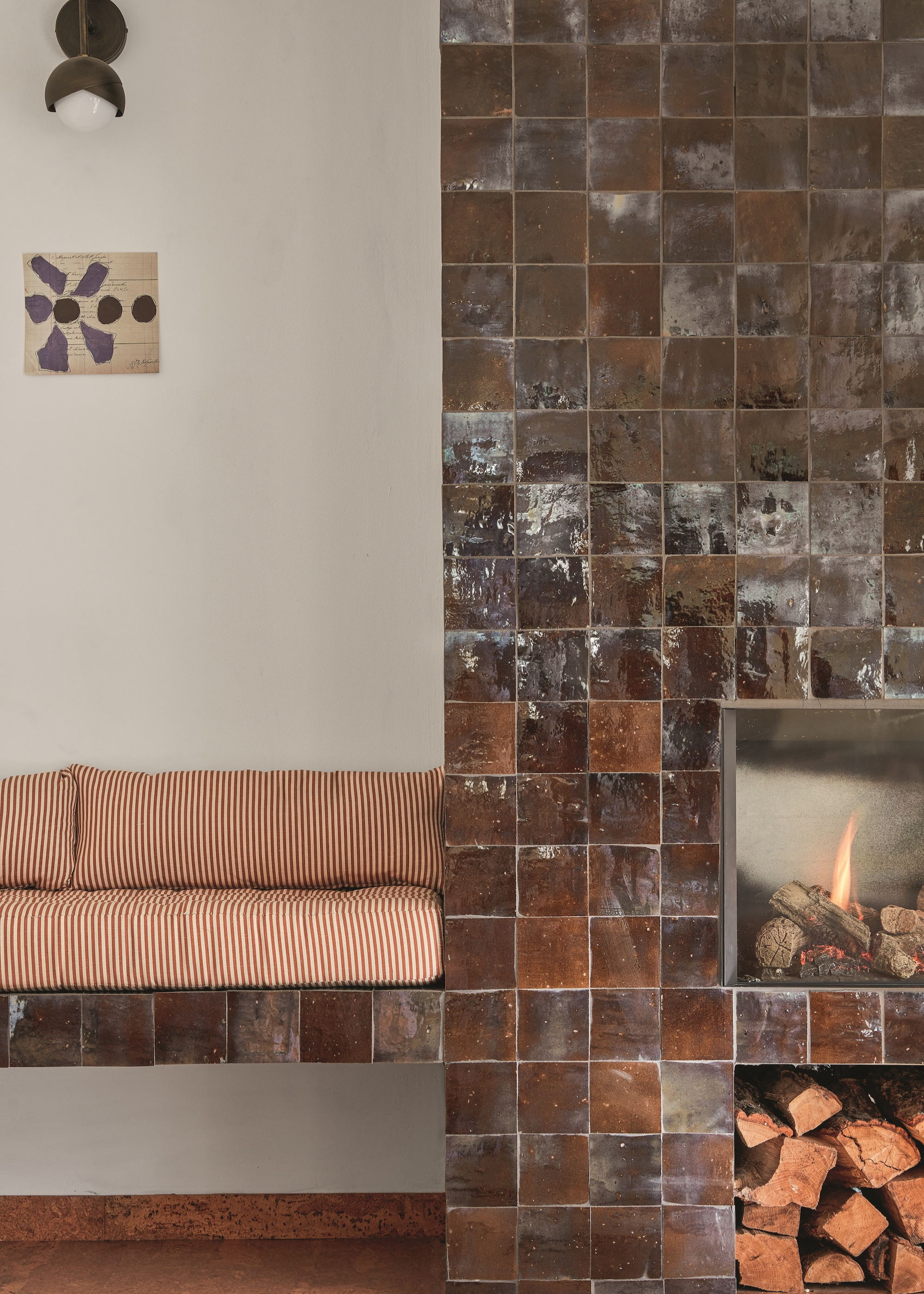 Brown, square tiled fire place with built in bench seat to the left, with striped, fabric cushion seat.