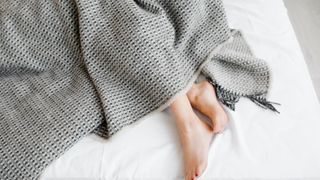 female feet under blanket flat lay