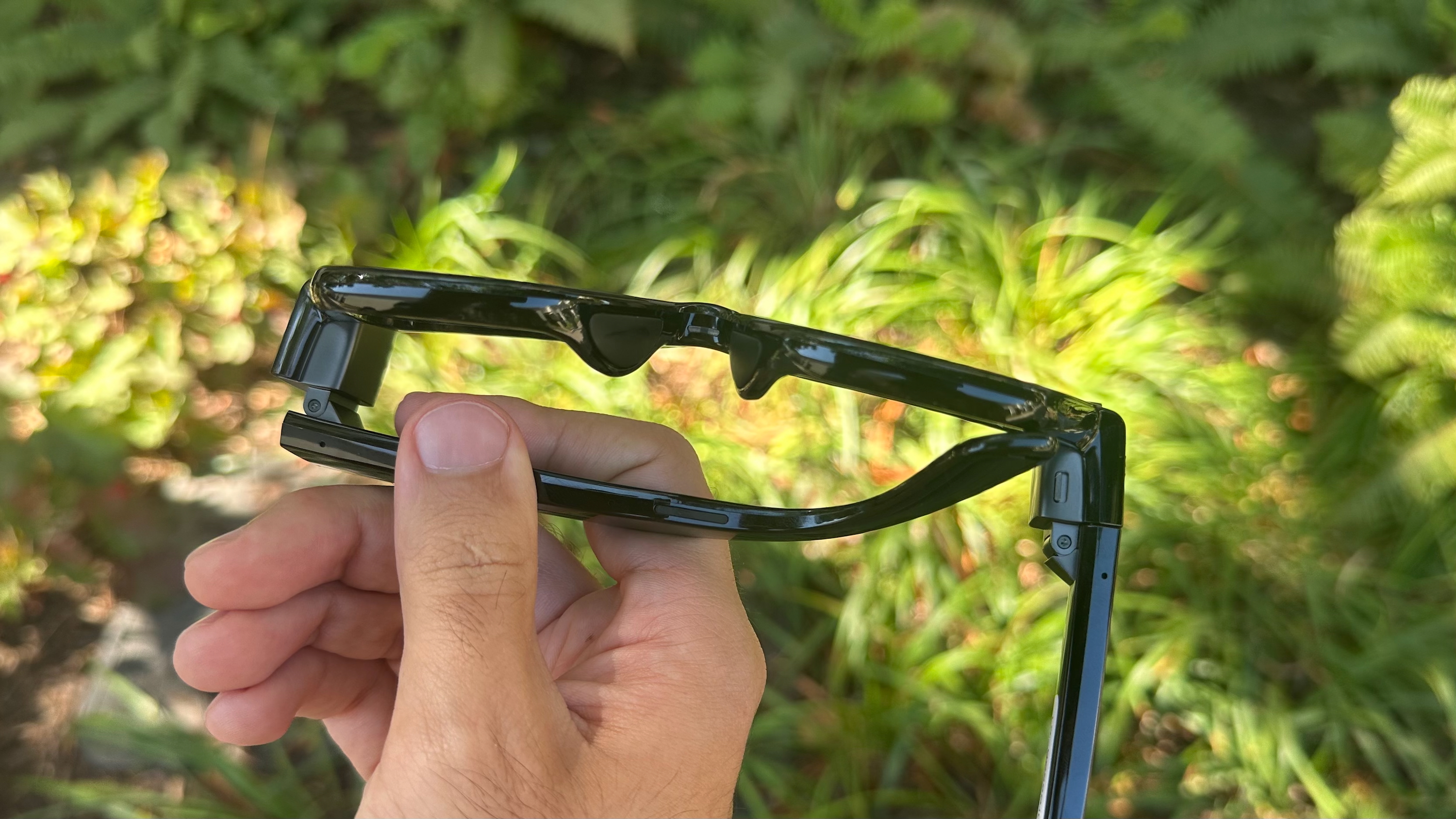 A photo of the Meta Ray-Ban Display glasses held upside down to show the nose bridge and arms.