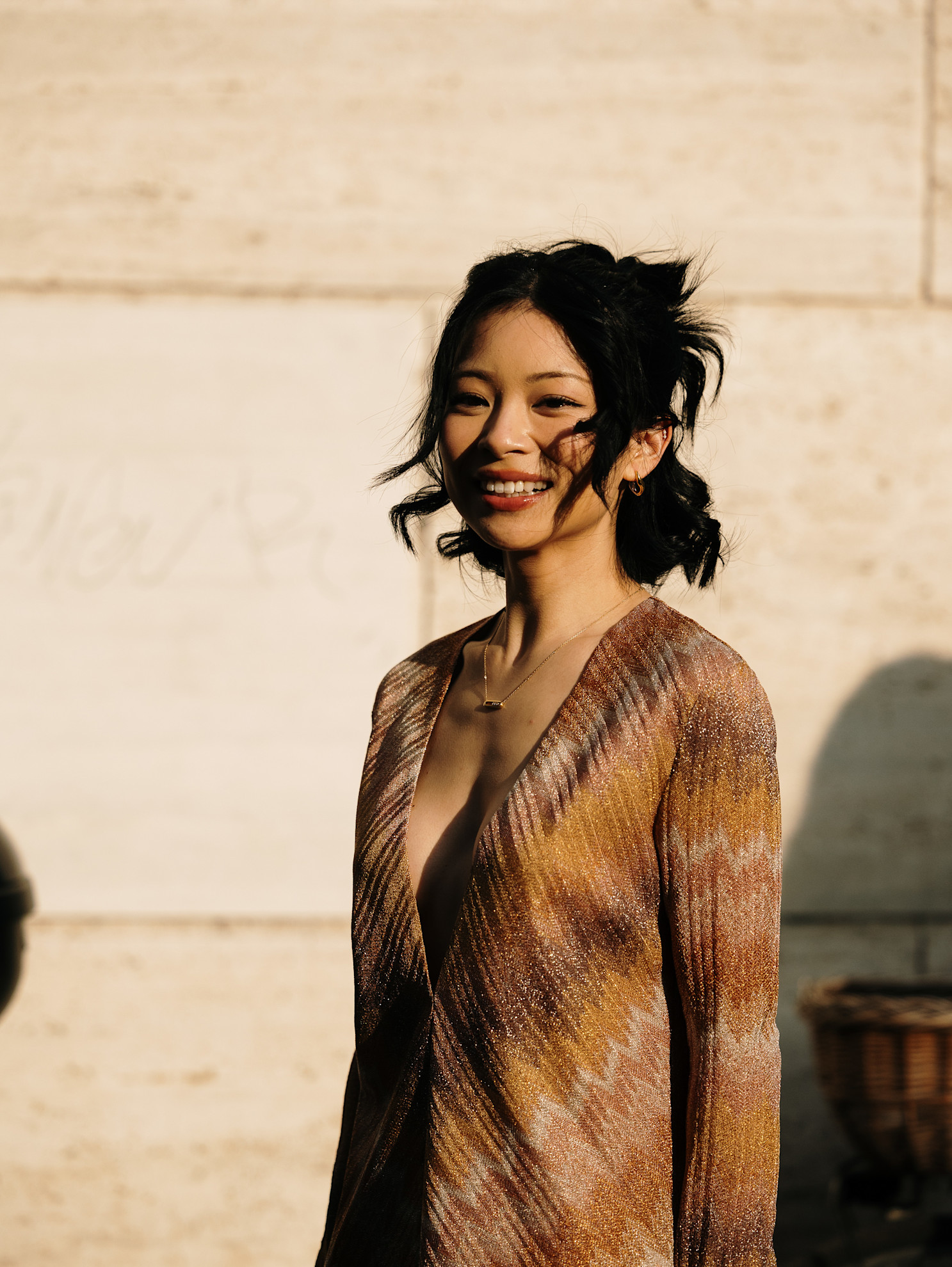 a woman in a bronze sparkly dress with a dark lob hairstyle