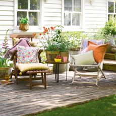 Garden chairs on decking in front of white clapboard house