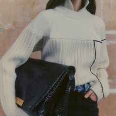 Woman wearing Moda Operandi white knit sweater and carrying large oversized black bag