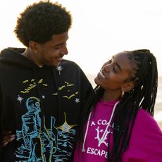 michael cooper jr as justin looking and smiling down at lovie simone as keisha as they walk on the beach in the series forever