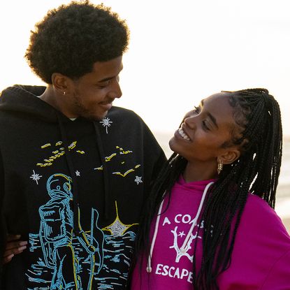 michael cooper jr as justin looking and smiling down at lovie simone as keisha as they walk on the beach in the series forever