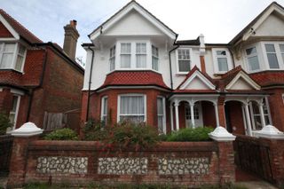 The front of the house shows a brick build home with white pillars and a triangular shaped roof