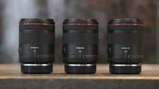 Canon RF 50mm F1.4L VCM and Canon RF 24mm F1.4L VCM lenses alongside the 35mm version on a rustic worktop