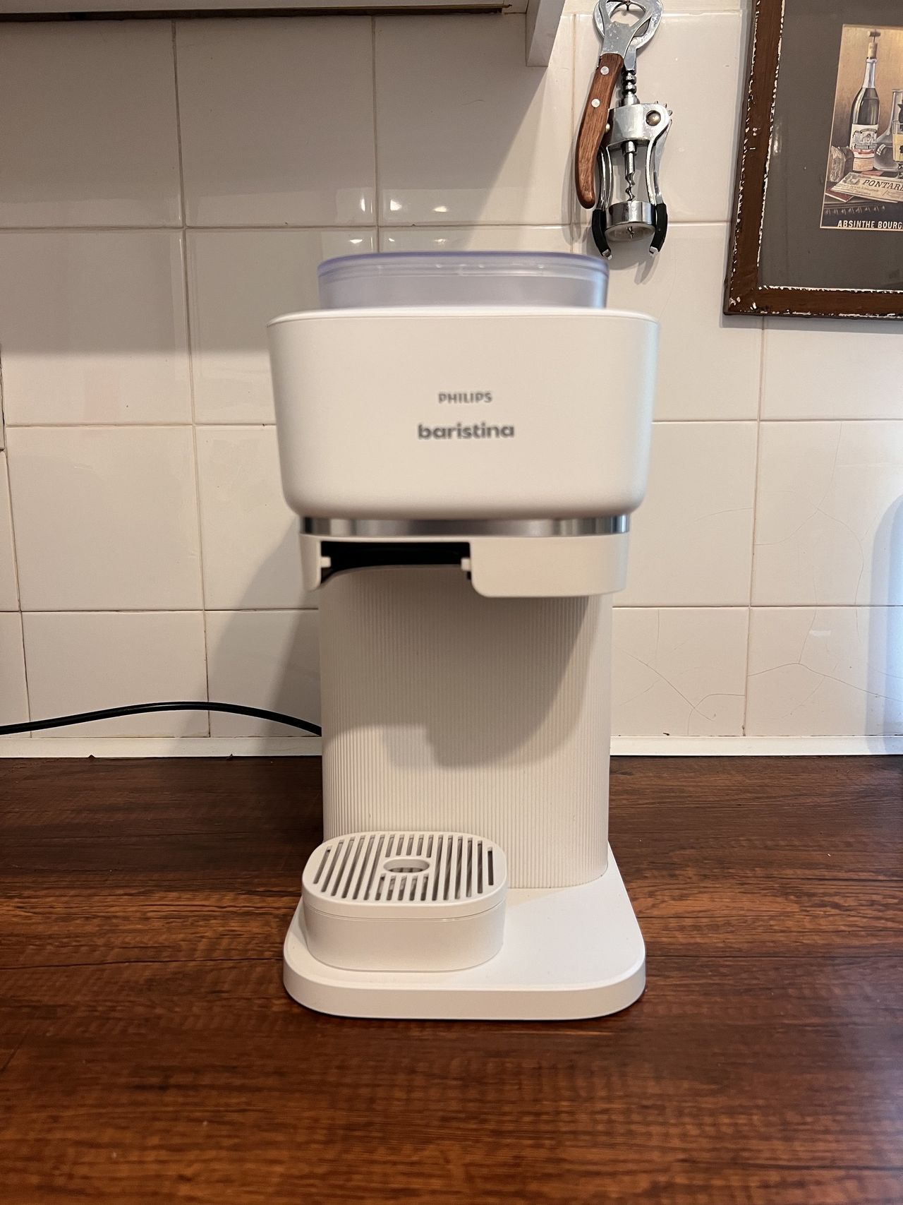 A while Philips Baristina coffee machine on a wooden countertop in a white kitchen.