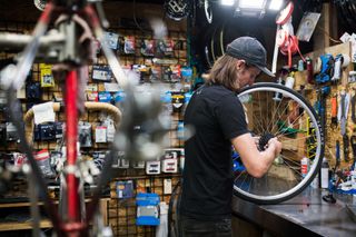 Man in workshop fixing bike wheel