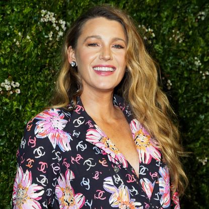 Blake Lively wears a chanel suit covered in double c logos and flowers while in front of a garden wall