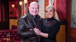 David Gillespie returns to EastEnders as Duncan Boyd - seen here standing in the Vic in a leather jacket next to a smiling Letitia Dean (Sharon Watts)